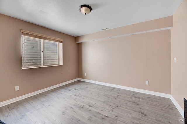 spare room with visible vents, baseboards, and wood finished floors