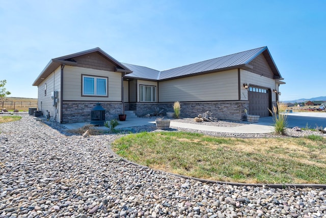 view of front facade featuring a garage, stone siding, and metal roof