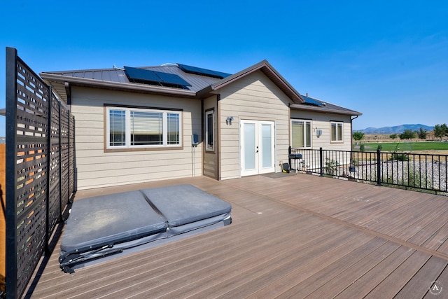 deck with a covered hot tub, french doors, and a mountain view