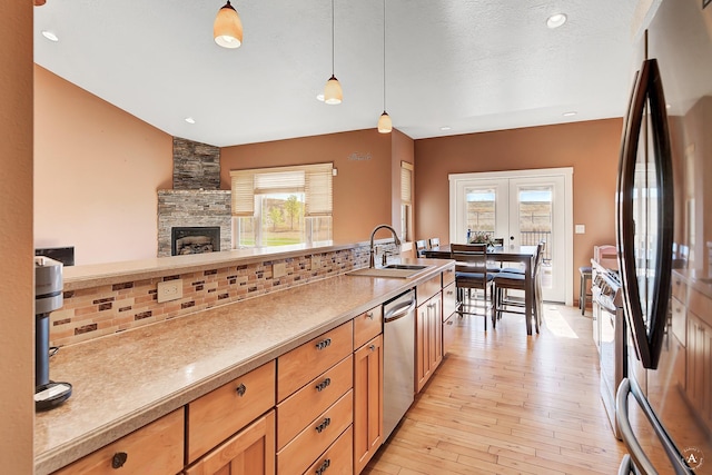 kitchen with hanging light fixtures, stainless steel appliances, light countertops, a healthy amount of sunlight, and a sink