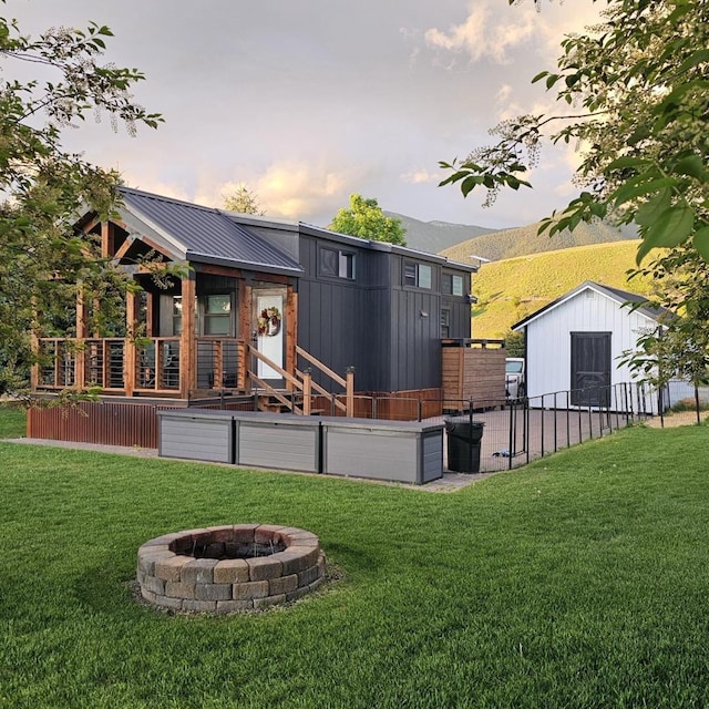 301 Kingfisher Loop, Eureka, MT 59917 - back of house at dusk featuring a fire pit, a storage shed, an outbuilding, a mountain view, and metal roof