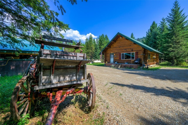 rear view of house featuring driveway and log siding