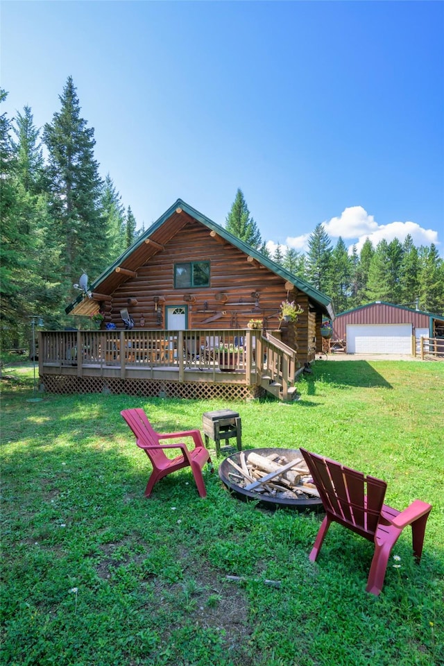 back of property with an outbuilding, a yard, an outdoor fire pit, log exterior, and a wooden deck