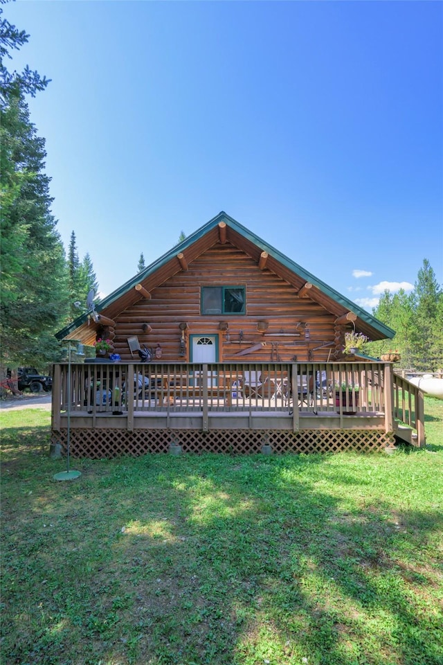 rear view of house featuring log exterior, a lawn, and a deck