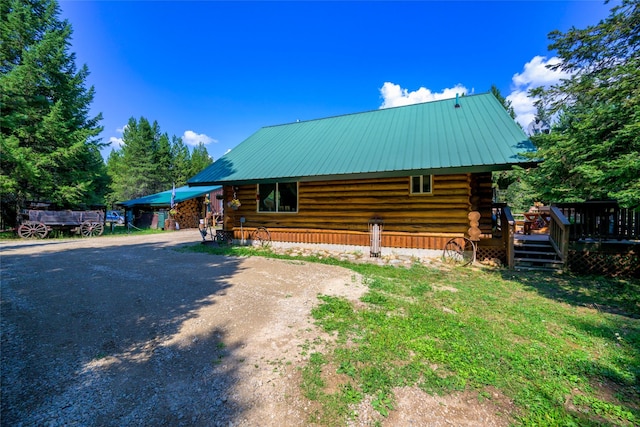 exterior space with metal roof, driveway, and log siding