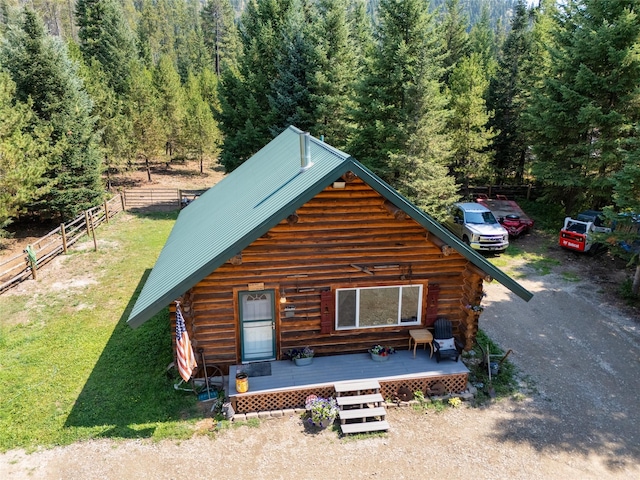 view of front of property with metal roof, fence, dirt driveway, log siding, and a front lawn