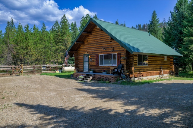 view of front of home with driveway, metal roof, and log exterior