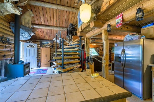 kitchen featuring wood ceiling, tile counters, stainless steel fridge with ice dispenser, beamed ceiling, and a wood stove