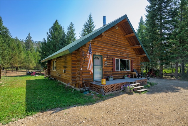 exterior space featuring driveway, a lawn, and log siding