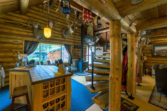 interior space featuring a wood stove, stairs, beamed ceiling, and wood finished floors