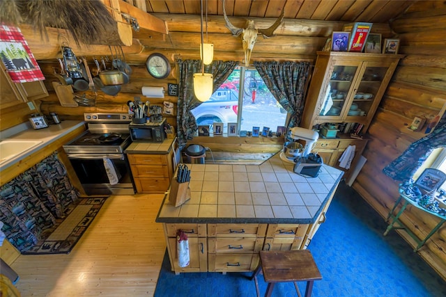 kitchen featuring pendant lighting, stainless steel electric range oven, tile countertops, glass insert cabinets, and black microwave