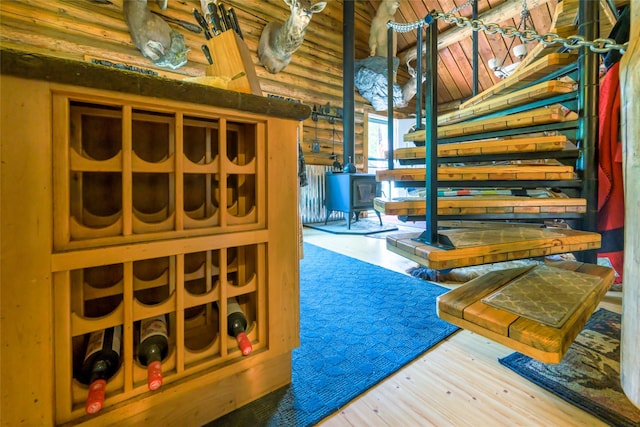 wine cellar featuring rustic walls, wooden ceiling, a wood stove, and wood finished floors