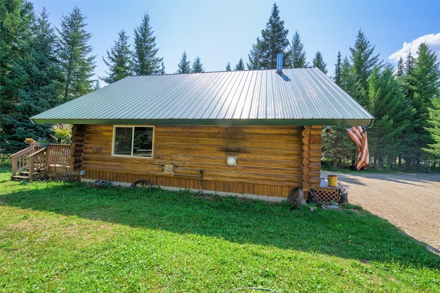 view of side of property featuring driveway, metal roof, log exterior, and a yard