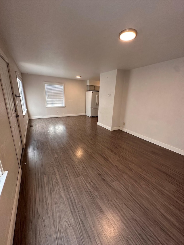 unfurnished living room with dark wood finished floors and baseboards