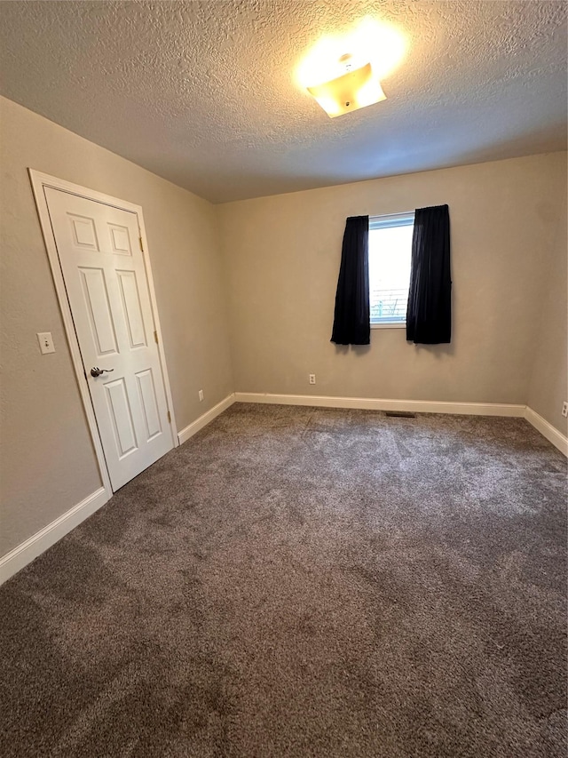 carpeted empty room featuring visible vents, a textured ceiling, and baseboards