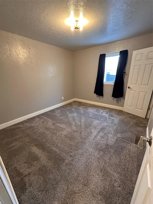 carpeted empty room with baseboards and a textured ceiling