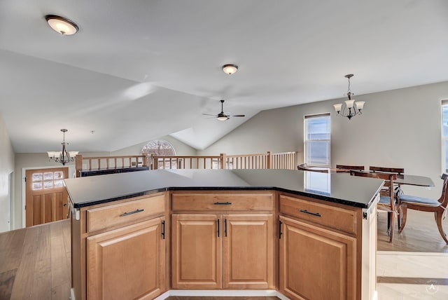 kitchen featuring dark countertops, lofted ceiling, hanging light fixtures, light wood-style flooring, and a kitchen island