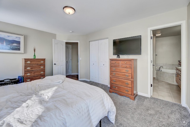 tiled bedroom featuring a closet, carpet flooring, baseboards, and ensuite bathroom