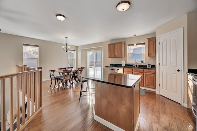 kitchen featuring dark countertops, a kitchen island, a kitchen breakfast bar, wood finished floors, and pendant lighting