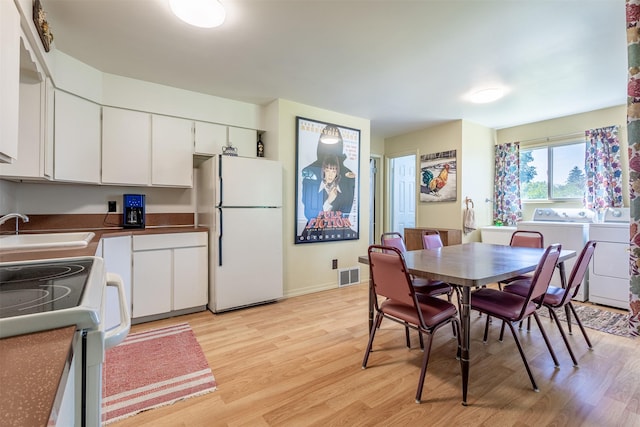 dining area with separate washer and dryer, visible vents, and light wood-style floors