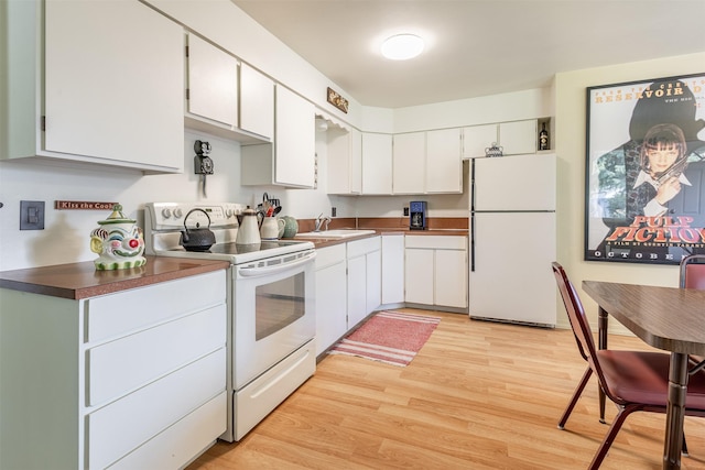 kitchen with light wood-type flooring, white appliances, white cabinets, and a sink