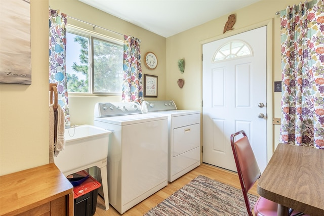 laundry area with laundry area, washing machine and dryer, and light wood-style flooring