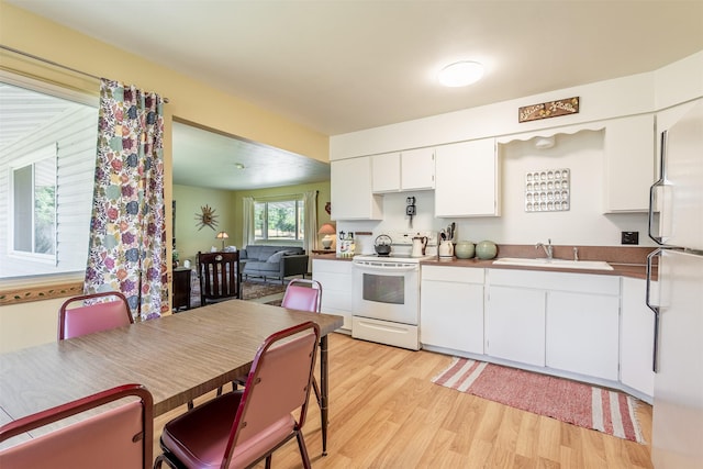 kitchen featuring light wood-style floors, white appliances, white cabinetry, and a sink