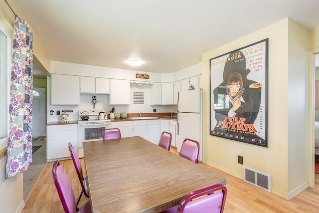 dining space with light wood-style floors, visible vents, and baseboards