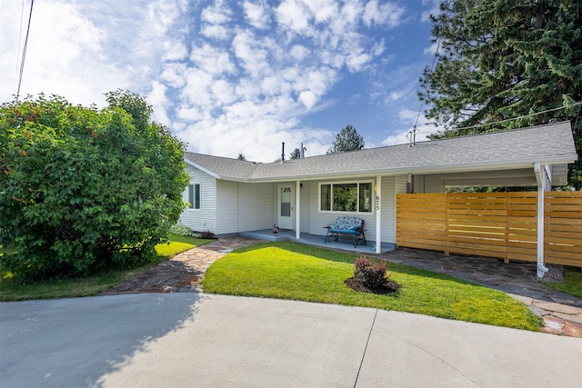 ranch-style home with a shingled roof, a front yard, covered porch, and fence