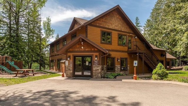 exterior space with stone siding, french doors, and a playground