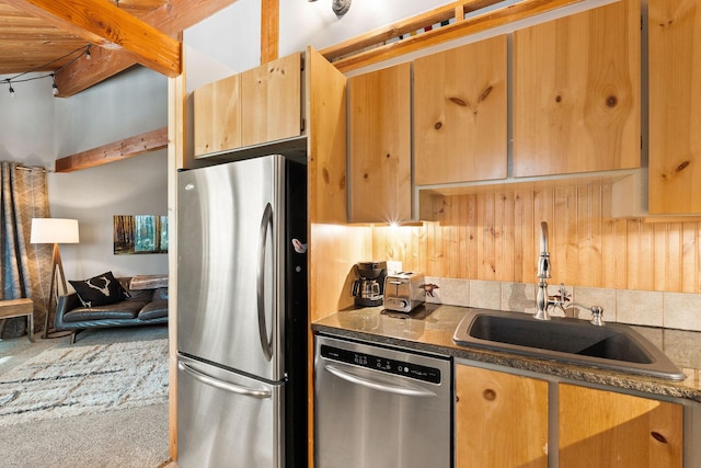 kitchen featuring dark countertops, beam ceiling, appliances with stainless steel finishes, and a sink