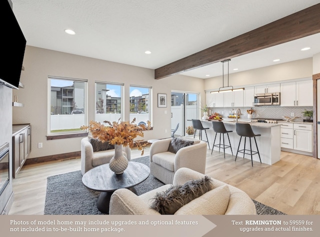 living room featuring light wood finished floors, baseboards, beamed ceiling, and recessed lighting