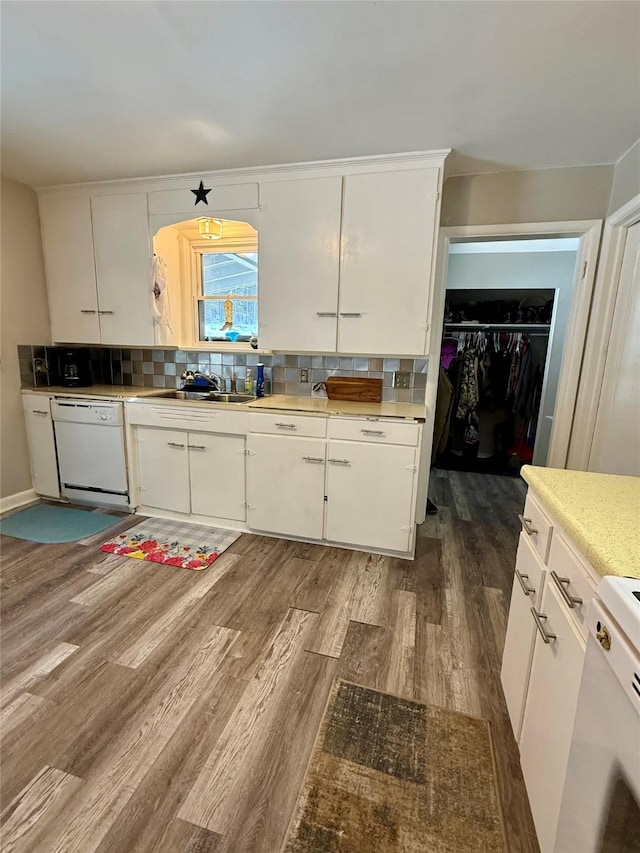 kitchen with tasteful backsplash, white dishwasher, light countertops, light wood-style floors, and white cabinetry