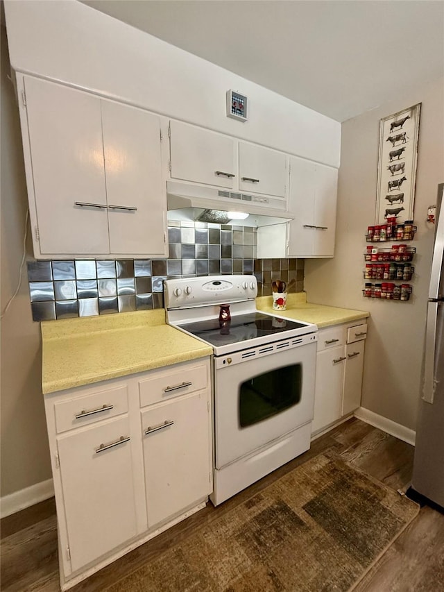 kitchen featuring under cabinet range hood, white electric range, light countertops, freestanding refrigerator, and decorative backsplash