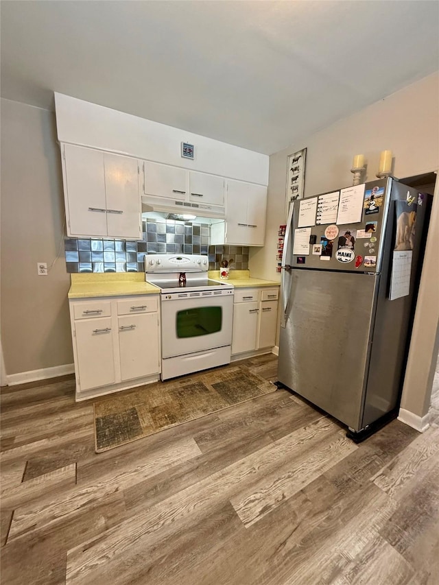 kitchen featuring white electric range oven, wood finished floors, freestanding refrigerator, light countertops, and white cabinetry