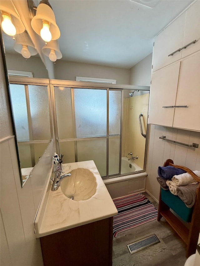 bathroom with vanity, combined bath / shower with glass door, wood finished floors, and visible vents