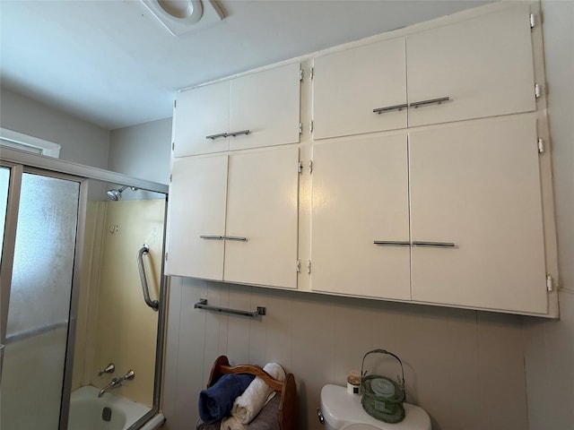 bathroom with toilet and combined bath / shower with glass door