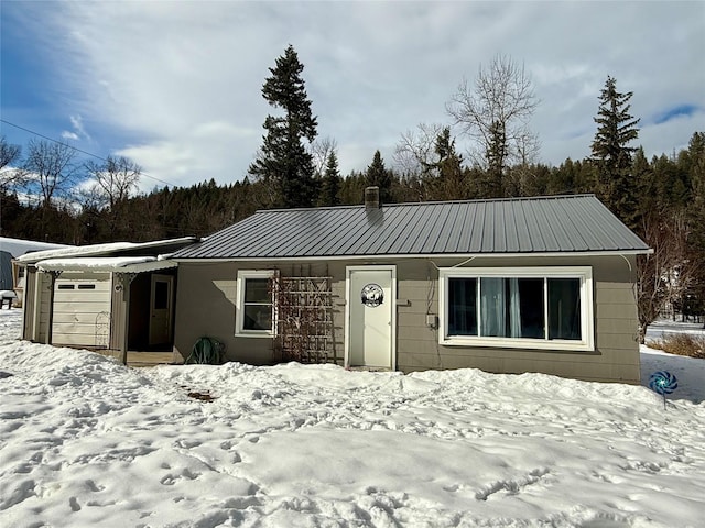 single story home with a garage and metal roof