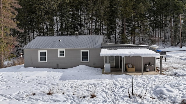 snow covered back of property featuring metal roof