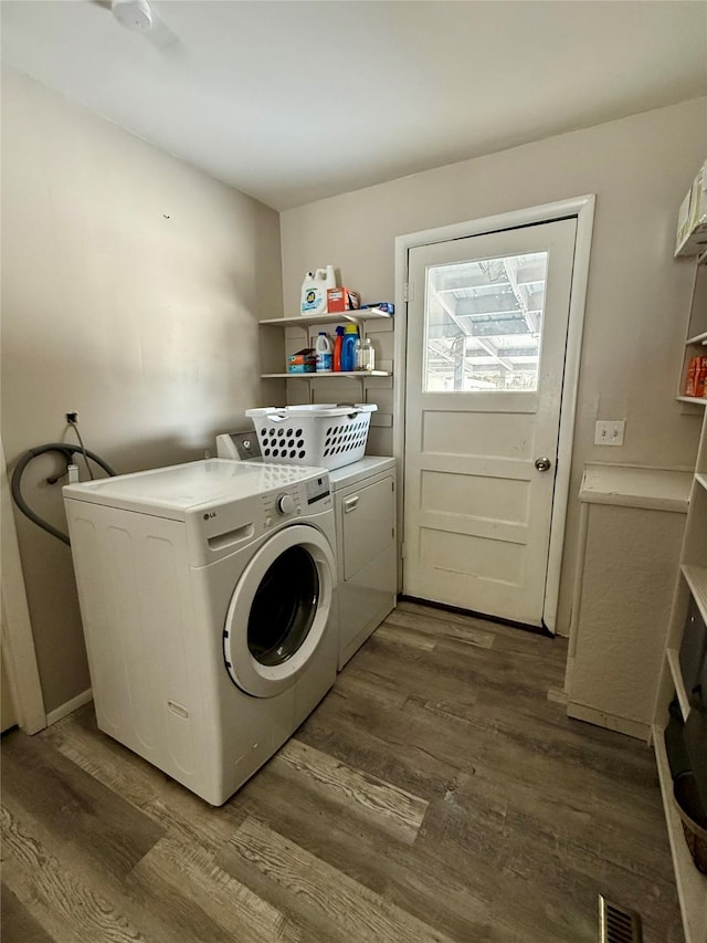 clothes washing area featuring dark wood-style floors, washer and dryer, laundry area, and visible vents