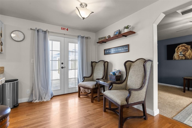 living area featuring light wood-type flooring, plenty of natural light, baseboards, and french doors