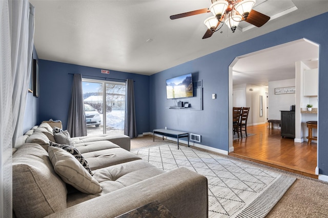 living room featuring visible vents, baseboards, arched walkways, ceiling fan, and light wood-type flooring