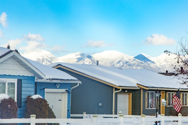 ranch-style house with a fenced front yard, a mountain view, and an attached garage