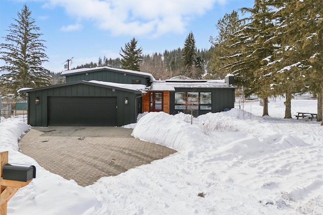 view of front of house with an attached garage, decorative driveway, and board and batten siding