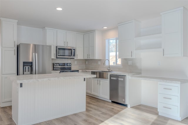 kitchen with a center island, light countertops, appliances with stainless steel finishes, white cabinets, and a sink