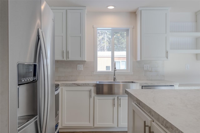 kitchen featuring stainless steel appliances, backsplash, a sink, and white cabinetry