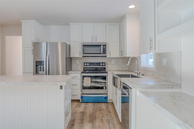 kitchen featuring light countertops, appliances with stainless steel finishes, a sink, and white cabinets