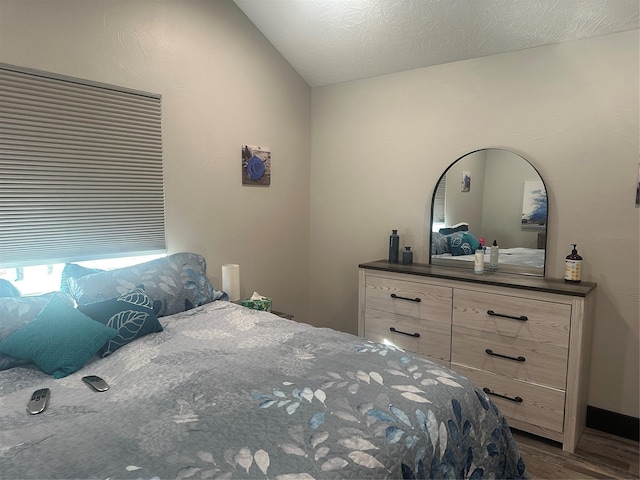 bedroom featuring a textured ceiling, vaulted ceiling, and dark wood-type flooring