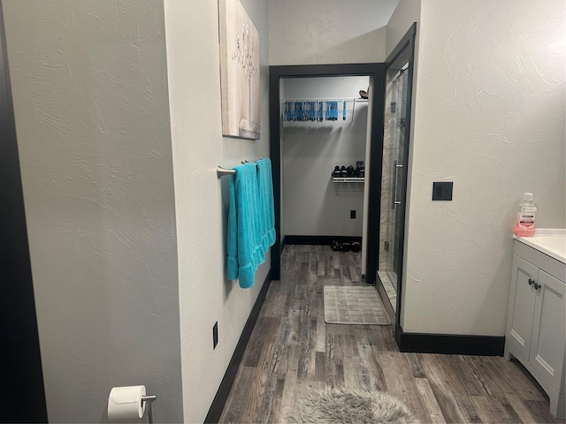 bathroom featuring a textured wall, wood finished floors, vanity, and baseboards