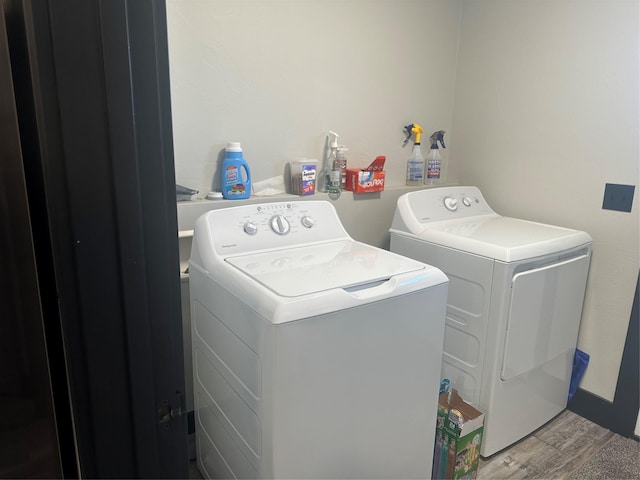 clothes washing area featuring laundry area, wood finished floors, and washing machine and dryer